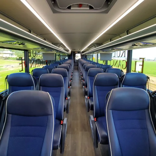 Charter bus passenger cabin True Elegance charter bus interior with rows of blue reclining seats and overhead luggage racks